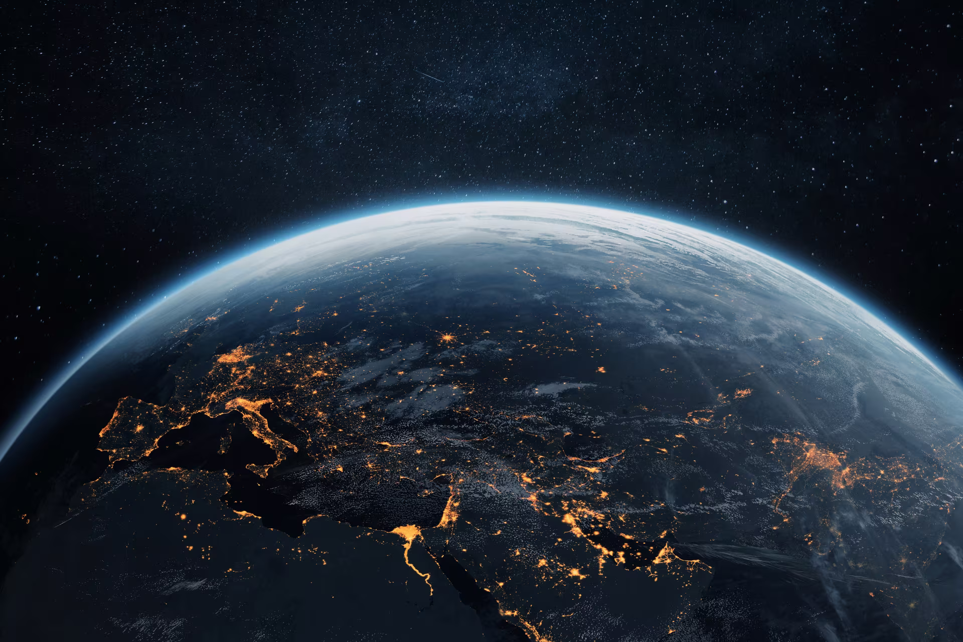 The Earth at night seen from orbit, city lights spanning Europe, the Gulf and Asia.